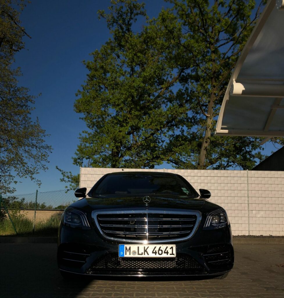 Schwarzer Mercedes-Benz S-Klasse, Frontansicht mit Kühlergrill und Stern-Emblem, geparkt vor weißer Mauer